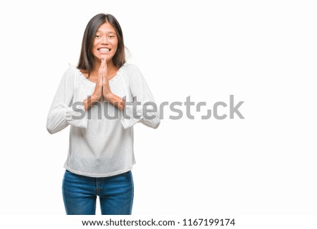 Young asian woman over isolated background praying with hands together asking for forgiveness smiling confident.