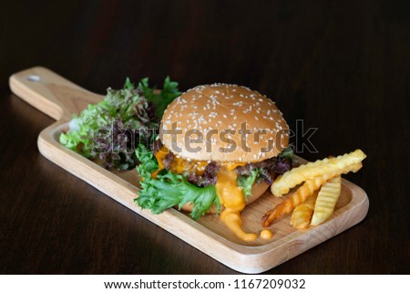 Hamburger with vegetables in wooden tray on dark wooden background / Select focus and space for texts


