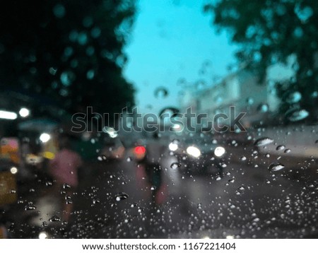 Blurry image, Rain drops on car windshield, traffic in the city on a rainy day at night. Colorful bokeh.
