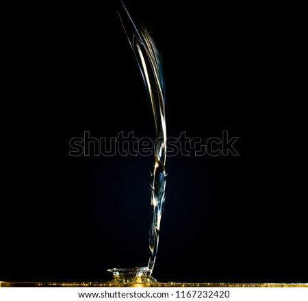 Close-up of oil and liquid pouring on dark background. Studio shutter freeze photography