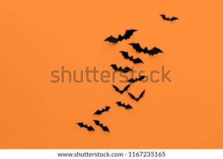 halloween decorations concept - many black paper bats on orange background
