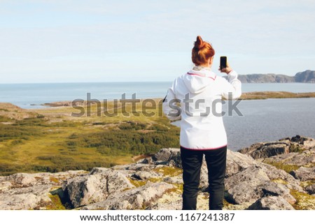 woman taking pictures on the phone sea and mountains