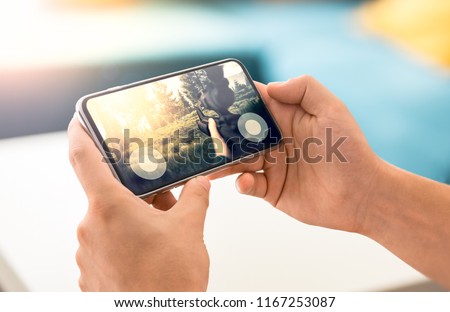Man playing fps game on frameless modern smartphone Royalty-Free Stock Photo #1167253087