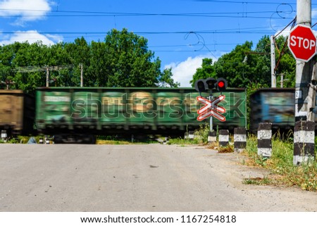 Railroad crossing sign and blinking semaphore in front of railroad crossing. Blurred motion of train