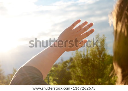 A young woman protects her eyes and skin from the sun with her hands. Sunlight, outdoor. Royalty-Free Stock Photo #1167262675