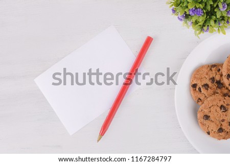 Empty card with and cookies on white wooden background