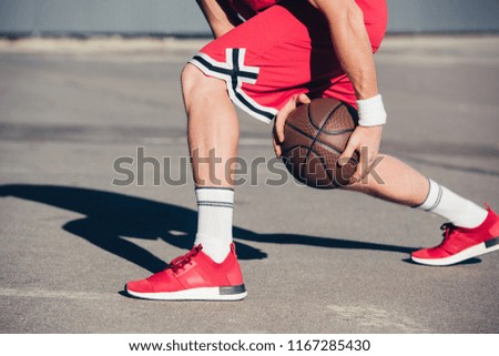 cropped image of basketball player playing basketball on street