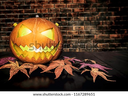 Halloween pumpkin on black wooden table with brick background. Halloween holiday concept.