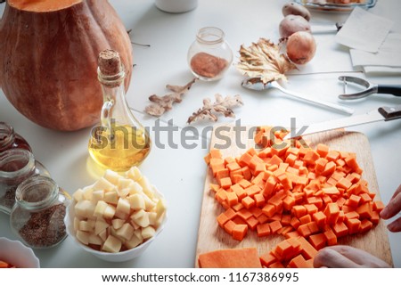Woman hands chopping carrot on wooden board, close up