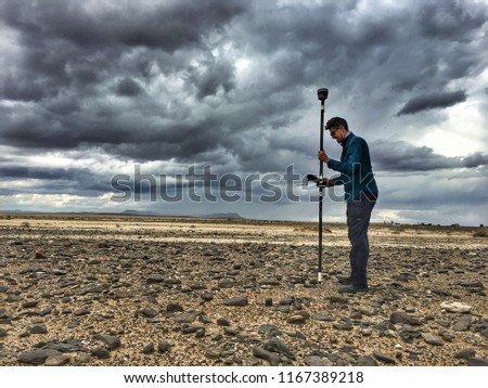 A land surveyor mapping an area in the desert with a trimble gps rover survey equipment