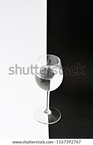 The water contained in a wine glass breaks the black and white background in exactly the opposite direction - art to clarify light reflection through round bodies - concept in black and white