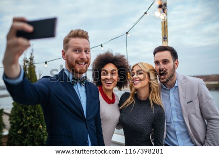 Four friends taking a picture with sell phone on rooftop