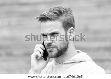 Man with beard walks with smartphone, urban background with stairs. Man with beard on serious face speaks on smartphone. Guy concentrated answer call on smartphone. Communication concept.