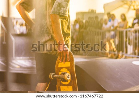 young rider holding a skateboard on a competition tournament