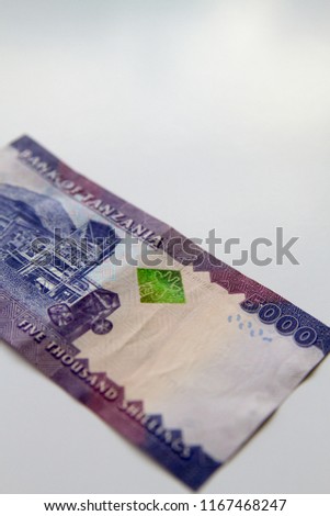 Colorful background of mixed banknotes and coins of Tanzanian Shilling with endangered wildlife on the back
