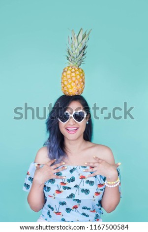 Make up cute.Girl with a pineapple on her head and glasses. , with a blue background. Tropical and summer vibes. Minimalist photoshot. Pastel colors and colorful photo shoot.