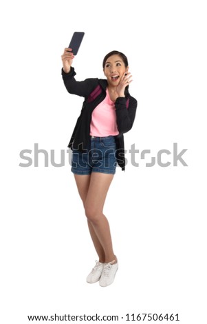 Full shots of cute asian girl in casual cloth holding mobile phone and take selfie in studio.