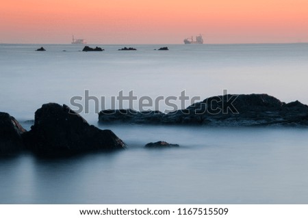 Long exposure of seascape rock beach in sunset background