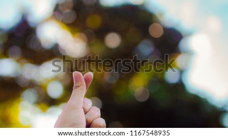 Mini heart hand sign with yellow leaves bokeh background