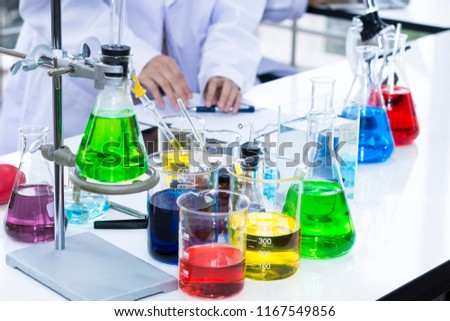Color water in test tube and beaker near microscope at laboratory.Copy space on white science lab.