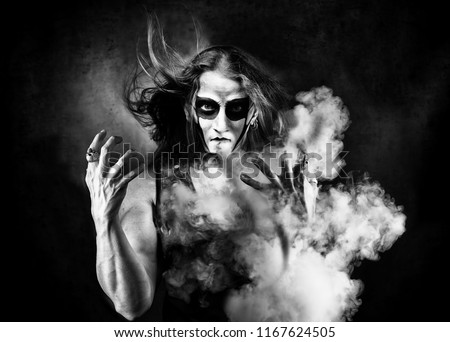 Portrait of man in goth style clothes with scull makeup. Blowing the smoke.