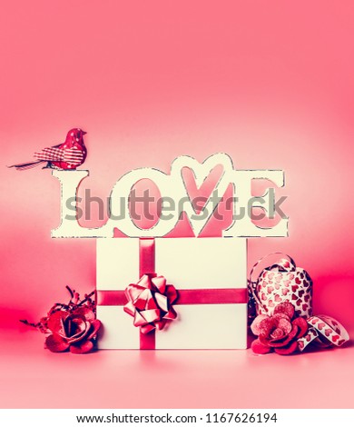 Word  LOVE with white gift box , red ribbon , heart and decoration , front view. Festive layout for greeting card