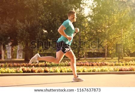 Young man running in park on sunny day