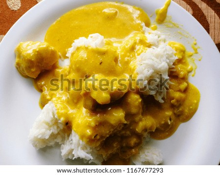 A picture of kadhi pakora, an Indian dish served  with rice on a simple white plate.