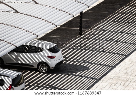 white clean cars on a parking lot in sunny summer day are under the shadows from the canopy falling on Royalty-Free Stock Photo #1167689347