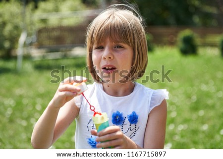 Happy little girl blowing soap bubbles