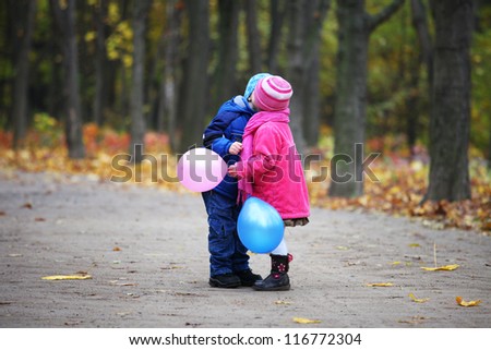 little girl and little boy kissing in autumn forest