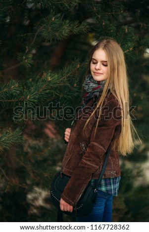 Blond girl walking in the park. Posing to the photographer.