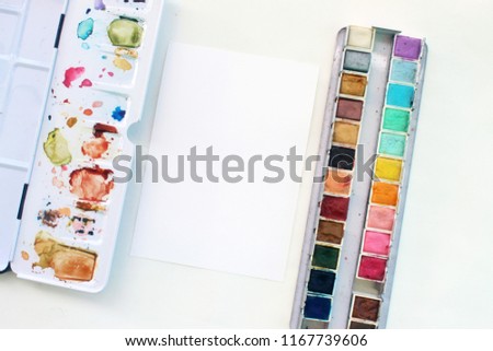 set of watercolor paints, brush, paper, and clip. watercolor mockup scene.