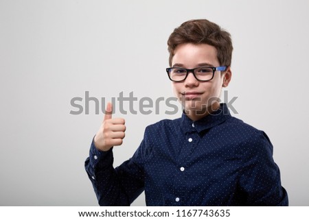 Schoolboy with glasses in closeup, showing thumbs up