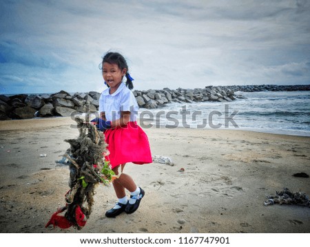 Baby girl is picking up the garbage by the sea. To reduce global warming is to help society.