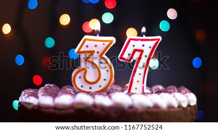 Happy Birthday.Holiday cake with candles.Birthday greetings.Greeting card.Colorful birthday candles.Thirty-seven years.Growing up.Abstract colorful background.Colorful bokeh.Top view.Stop motion.