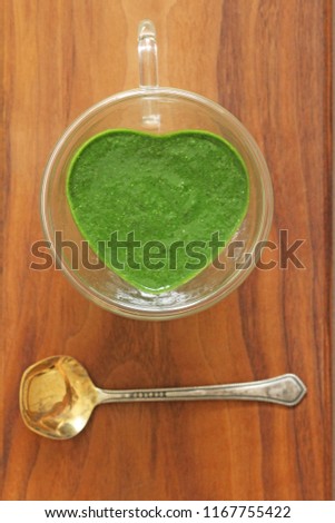 Spinach smoothie on wooden background. Fruit green smoothies in glass heart. Detox, diet, healthy, natural, organic food. Vintage gilded spoons. In the shape of a heart. Green smoothie. Copy space.