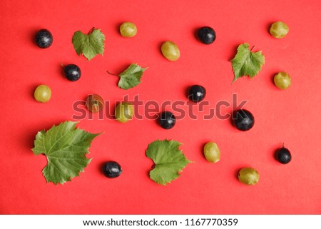 Fresh ripe juicy grapes and leaves scattered on color background, top view
