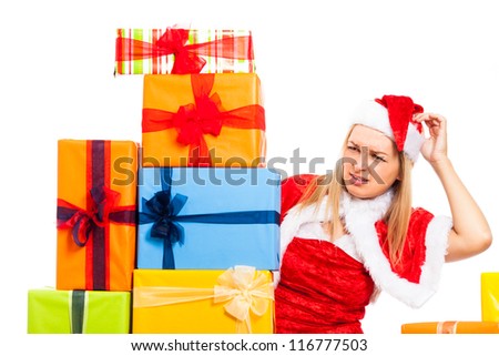 Young blond worried woman in Santa costume surrounded by Christmas gift boxes, isolated on white background.
