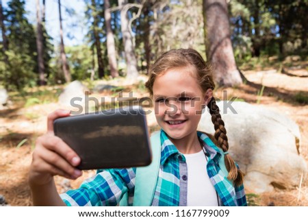 Smiling girl taking a selfie in the forest
