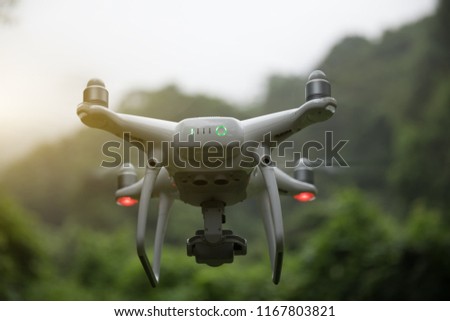 White drone with camera flying over forest