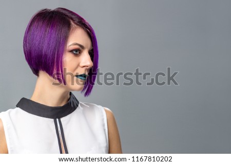 Fashion woman with purple short hair over gray background