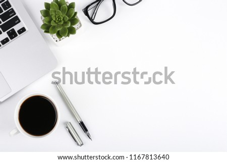 White office desk table with laptop computer, green plant, glasses and a cup of coffee. Top view with copy space, flat lay.