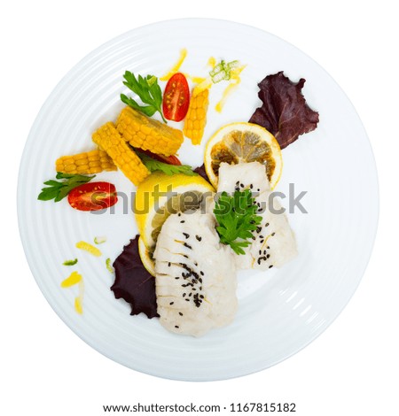 Steamed cod fillets served with corn, cherry tomatoes, parsley and lemon. Isolated over white background