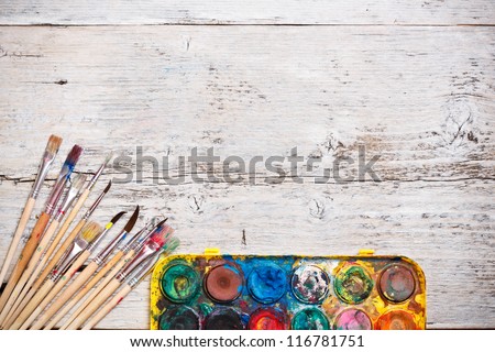 Watercolor paint and brushes on wooden background