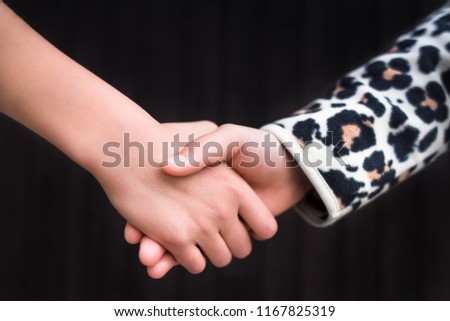 Deal or summer farewell closeup background image. Two school kids hold or shake their hands. Abstract friendship, help, children psychology and good bye or success in business agreements concepts.