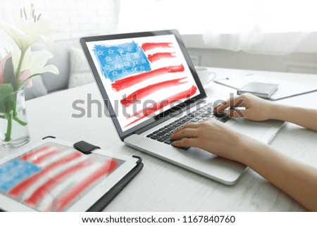 Young woman using laptop with American flag on screen at table