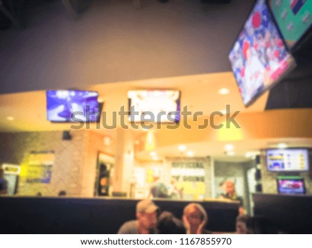 Blurred abstract sports bars restaurants in USA. Defocused people watch sports, drink beer, and eat American cuisine