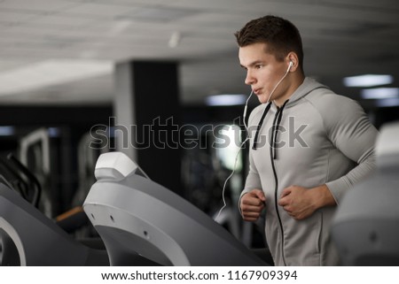 Handsome man in gym running on the treadmill