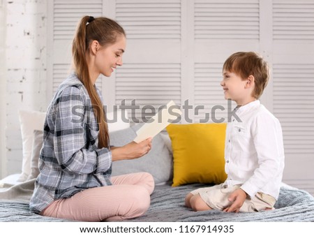 Cute little boy and his mother with handmade greeting card at home. Mother's day celebration